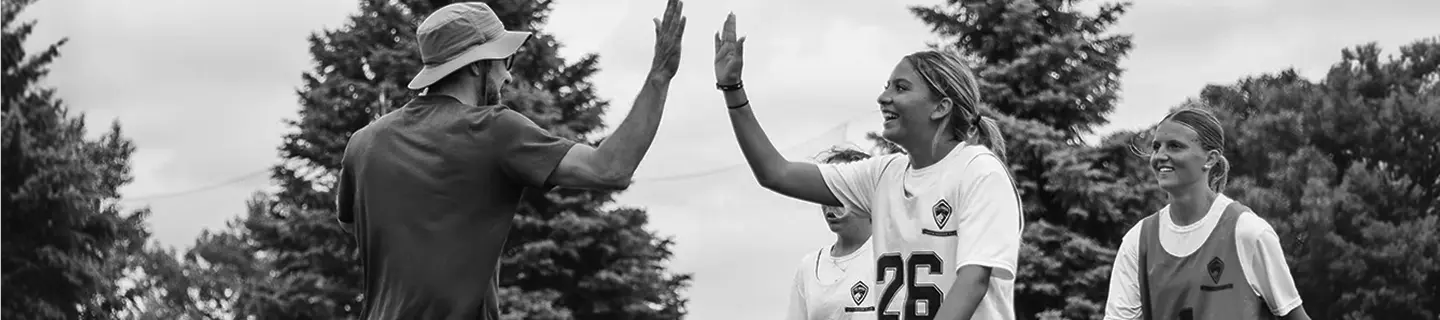A Colorado Storm coach gives a high five to a youth player during an outdoor soccer camp